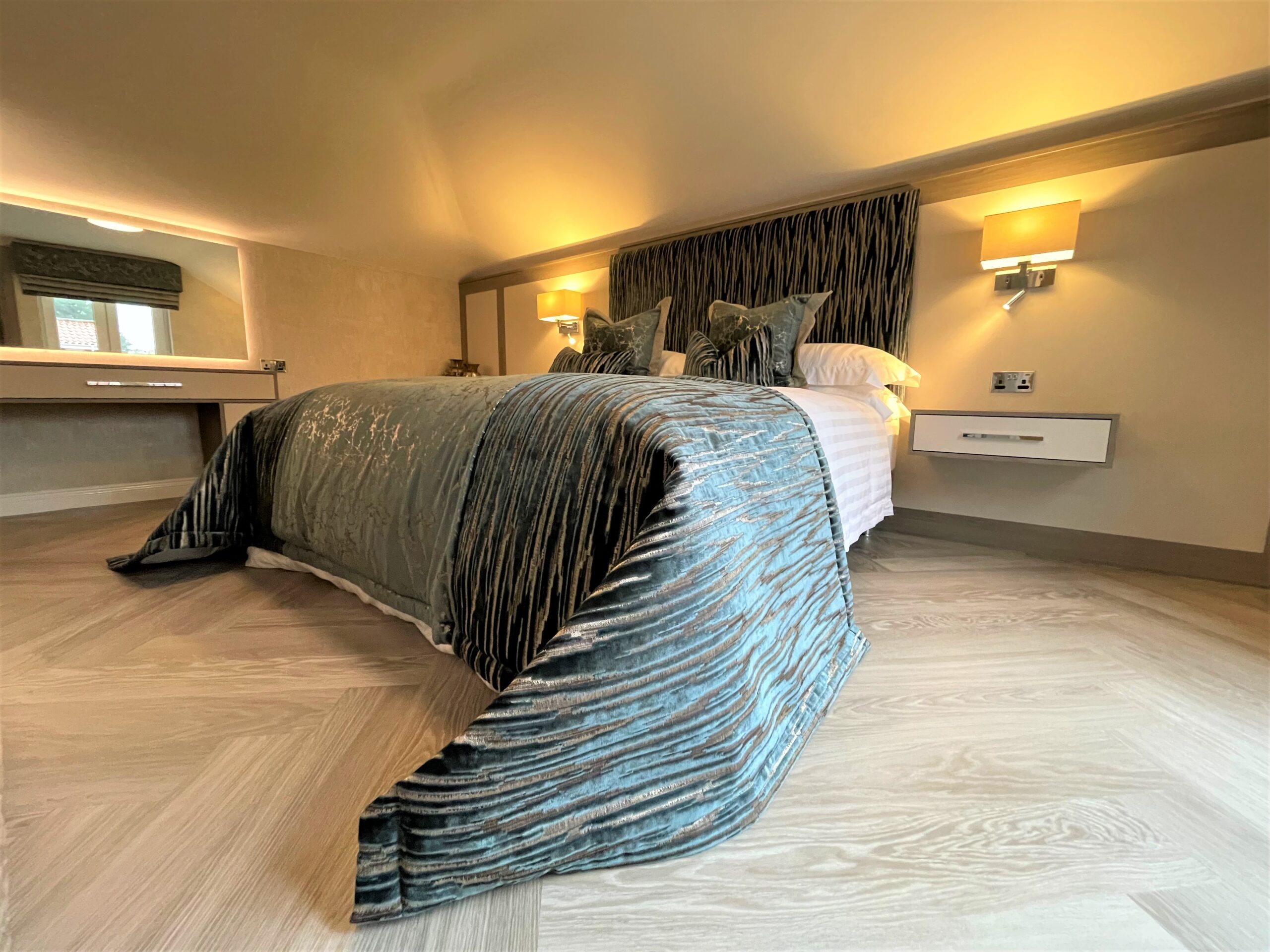 lavish guest bedroom with dressing table wall hung bedside cabinetry and media furniture